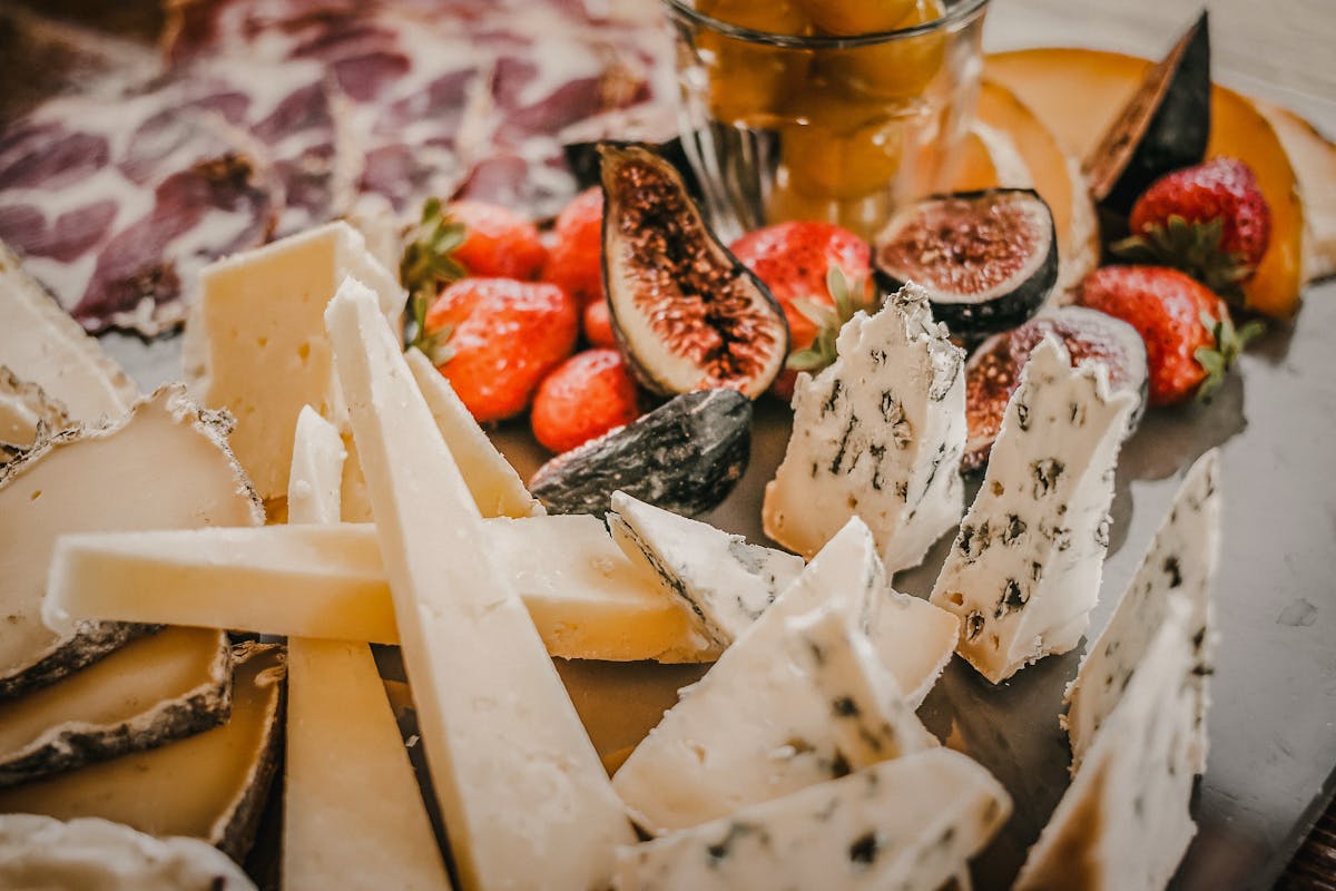 Plateau de fromages fermiers avec figues, fraises et charcuterie, Saint-Nectaire et Fourme d'Auvergne réunis