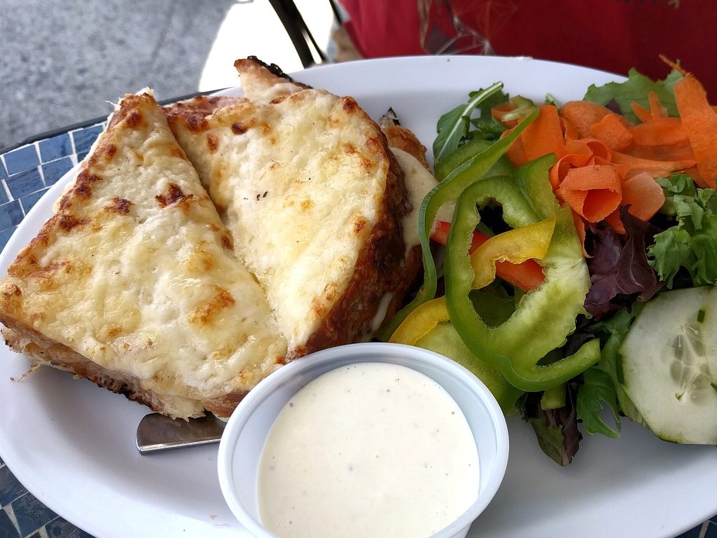 Croque-monsieur doré coupé en deux avec une salade