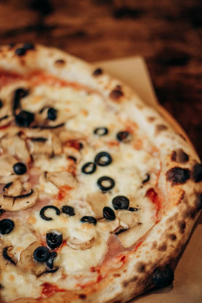Part de pizza dorée aux champignons frais et fromage fondu - pizza au Saint-Nectaire fermier